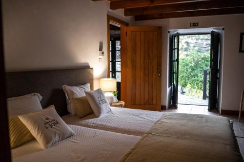 a bedroom with a large bed with white sheets and pillows at Quinta De São José in Ervedosa do Douro