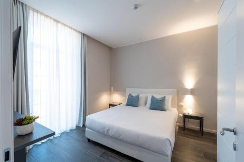 a bedroom with a white bed and a large window at Corte Novella Hotel & Residence in Brescia