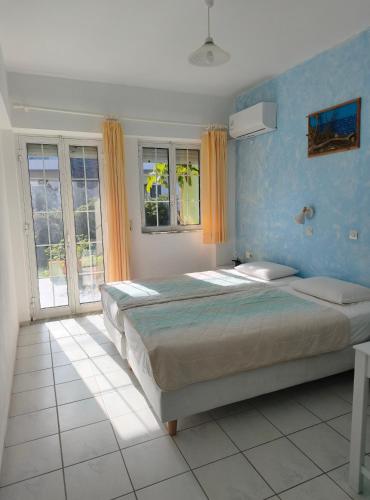 a bedroom with a large bed with blue walls and windows at Livadi Apartments in Plakias