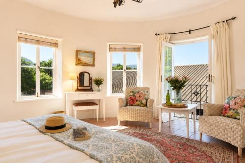 a bedroom with a bed and chairs and windows at Constantia The Silos in Sweet Valley