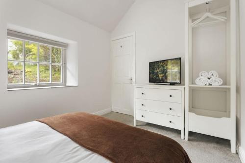 a white bedroom with a bed and a tv at The Cosy Cottage - Ridgestone in Bowness-on-Windermere