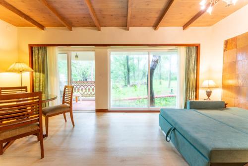 a bedroom with a bed and a table and a window at Club Mahindra Golden Landmark, Mysuru in Mysore