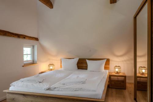 a bedroom with a large white bed with two lamps at Haus Tadder in Born