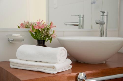 a bathroom with towels and a sink and a vase with flowers at Dolores Hotel - Uruguay in Dolores