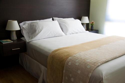 a bedroom with a large bed with white sheets and pillows at Dolores Hotel - Uruguay in Dolores