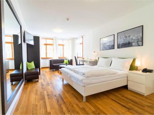 a bedroom with a white bed and a living room at The Square Coburg in Coburg