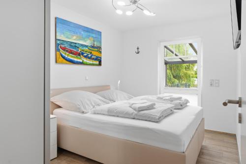 a white bedroom with a bed and a painting on the wall at Grachtenblick I in Greetsiel