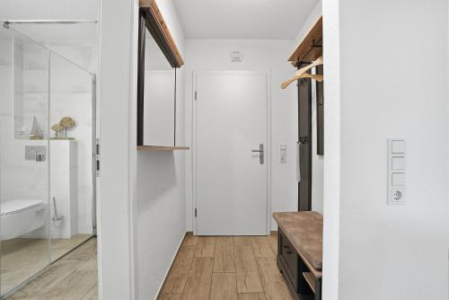 a bathroom with white walls and a glass door at Grachtenblick I in Greetsiel