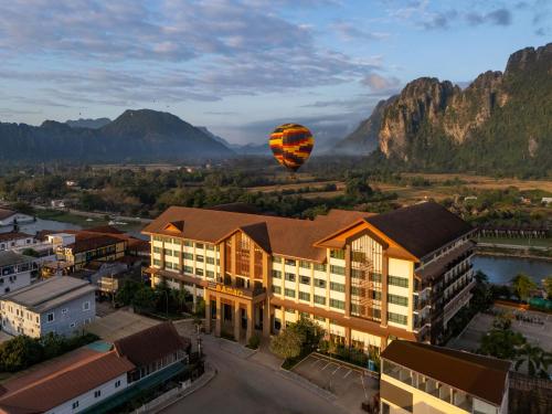 a hot air balloon flying over a town with mountains at Amari Vang Vieng in Vang Vieng