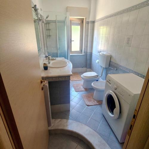 a bathroom with a toilet sink and a washing machine at Apartment Glam House Monet in Rometta Marea