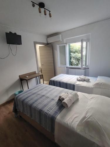 two beds in a room with a television and a window at Affittacamere Torresi in Ancona
