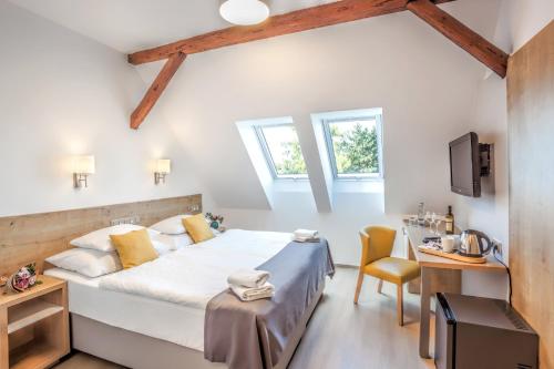 a bedroom with a bed and a desk and a tv at Hotel Slavia in Boskovice