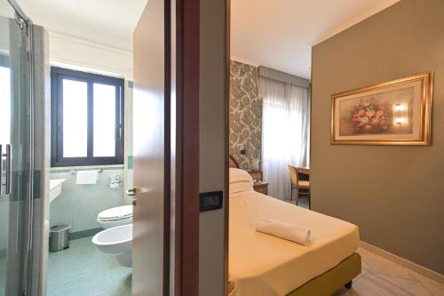 a bedroom with a bathroom with a toilet and a sink at Hotel L'Aquila in Pomezia