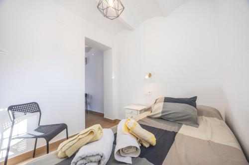 a white bedroom with a bed and a chair at Casa Socra in Arcos de la Frontera