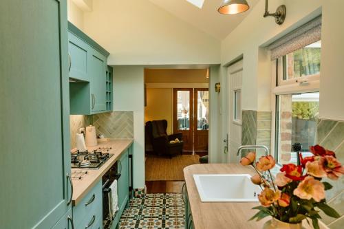 a kitchen with blue cabinets and a vase of flowers at Finest Retreats - 2 Haywood View in Grindleford Bridge