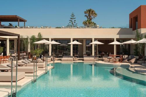 a swimming pool with lounge chairs and umbrellas at ARATO by E-GEO, Adults Only in Kos