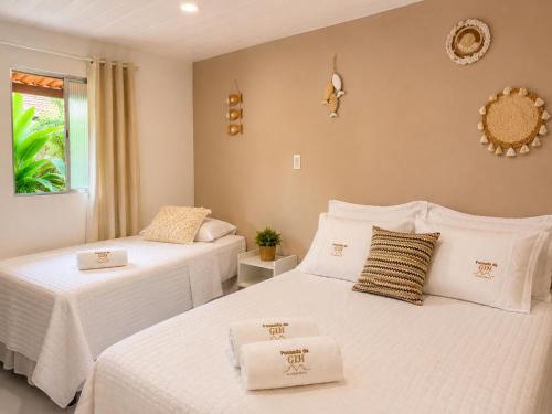 two beds in a room with white sheets at Pousada da Gih in Fernando de Noronha