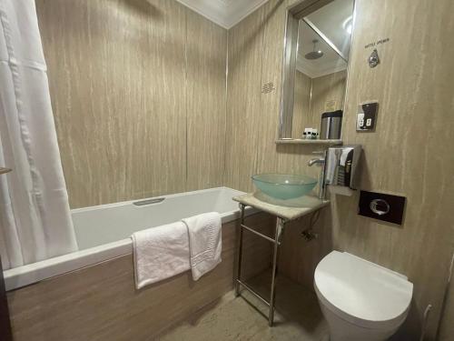 a bathroom with a tub and a sink and a toilet at The Mansefield Hotel in Elgin