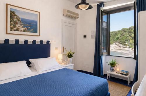 a bedroom with a blue bed and a large window at Hotel Baia Di Puolo in Massa Lubrense