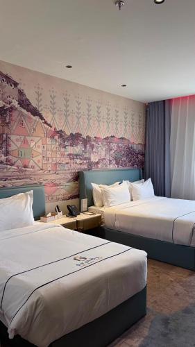 a hotel room with two beds and a painting on the wall at Golden New Hotel in Abha