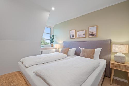 a bedroom with a large white bed with two pillows at Nordseebude Küstenglück in Sankt Peter-Ording