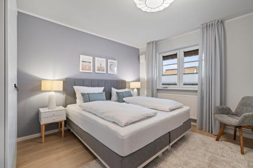 a bedroom with a large bed and a chair at Nordseebude Strandnest in Sankt Peter-Ording