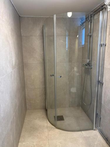 a shower with a glass door in a bathroom at Holma Stångenäs Golf in Brastad