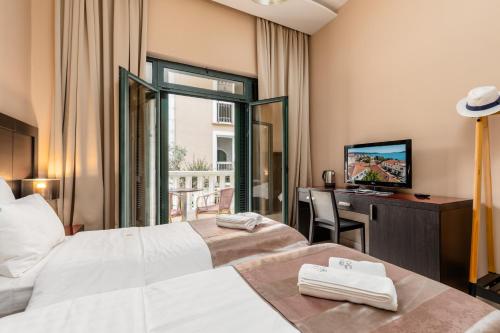 a hotel room with two beds and a desk and a television at Apartments Grifone Lux in Herceg-Novi