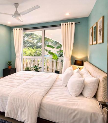 a large white bed in a room with a window at Rovio in Vagator
