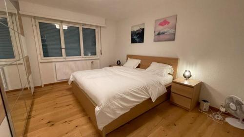 a bedroom with a large white bed and two windows at Plage & Montagne - Appartement familial à proximité de la plage de Préverenges in Preverenges