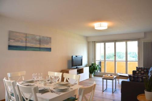 a dining room with a table and chairs and a television at Plage & Montagne - Appartement familial à proximité de la plage de Préverenges in Preverenges