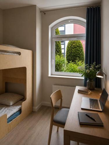 a room with a desk with a laptop and a window at Dzien Dobry Hostel in Gdańsk