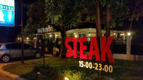 Un cartel de un restaurante de carnes por la noche. en Paklop Resort, en Lopburi