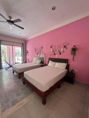 two beds in a room with a pink wall at Casa Sayab Hotel Boutique in Maní
