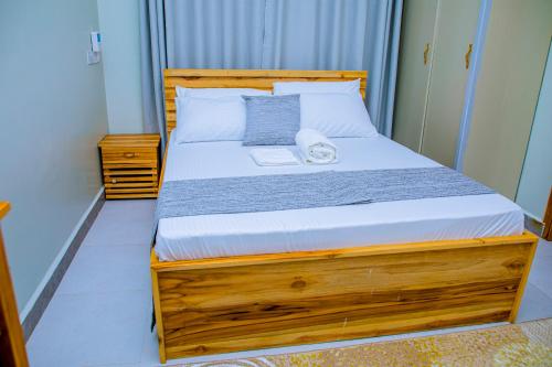 a bedroom with a bed with a wooden bed frame at ExtraMile Apartments - 2BR in Dodoma
