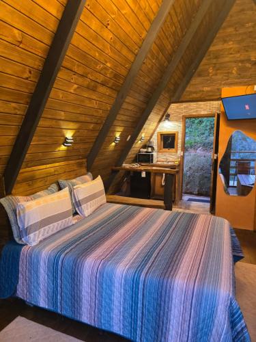 a bedroom with a bed in a wooden cabin at Chalé Cristal Capivari in Campos do Jordão