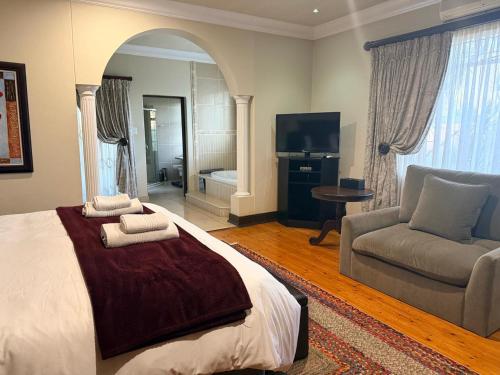 a bedroom with a bed and a couch and a television at Goodey's Guesthouse in Pretoria