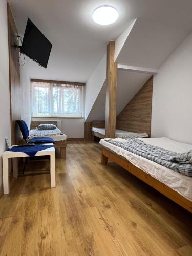 a room with two beds and a tv in it at Rezydencja pod Gwiazdami in Legarda