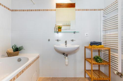 a white bathroom with a sink and a bath tub at Velvet Lipno in Lipno nad Vltavou