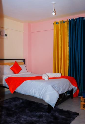 a bedroom with two beds and a yellow curtain at Magik Haven Studios Nyeri in Nyeri