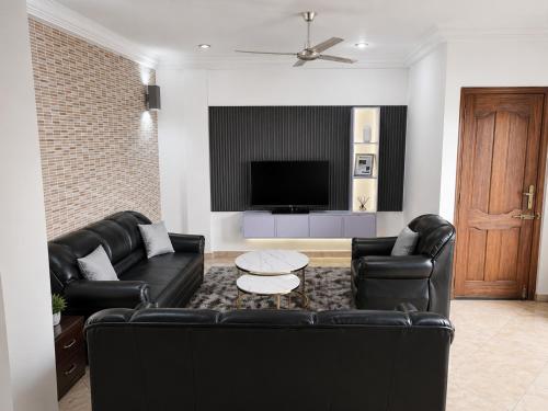 a living room with black leather furniture and a tv at Luxor Gardens Residences in Accra