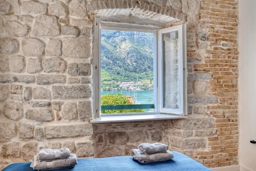 a stone walled room with a window and two pillows at Stunning Views & Hidden Terraces Above the Old Town in Kotor