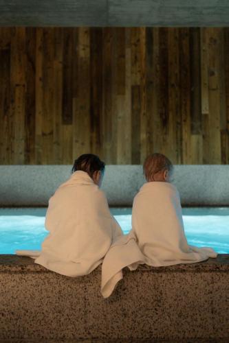 a couple of people sitting in a swimming pool at Runo Apartamenty & SPA - Basen Sauna - Odkryj-Białkę in Białka Tatrzańska