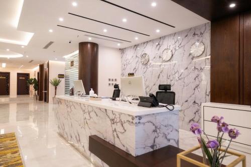 a lobby with a marble wall with a reception desk at Garden Melenium - Jazan in Jazan