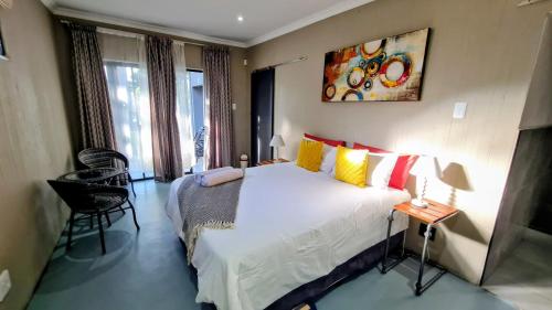 a bedroom with a large bed and a table and chairs at Kaleaba House on the Riverside in Parys