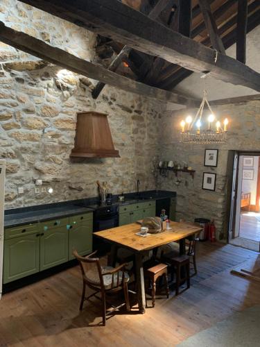 a kitchen with a wooden table and a stone wall at Manor House Dungeon in Chozendo