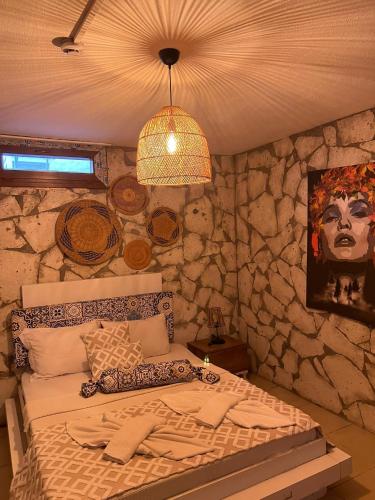 a bedroom with a stone wall with a bed at Mor Salkım Konağı in Alaçatı
