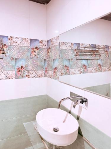 a white sink in a bathroom with mosaic tiles at Being Himalayan Chojh in Manīkaran