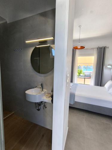 a bathroom with a sink and a bed and a mirror at Ioannis Fotinos Rooms in Lygia