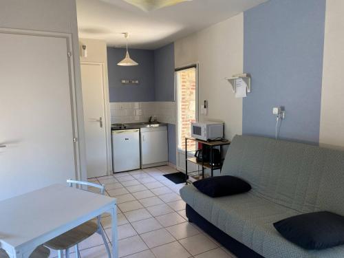 a living room with a couch and a kitchen at Meublé BLEU in Réaumur